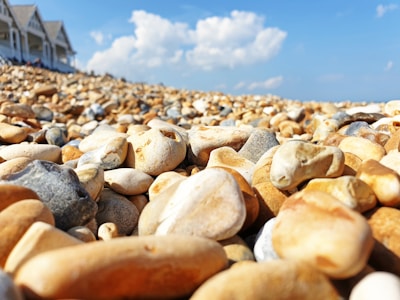 Wide view of a beach pebble quarry with workers selecting stones under a clear sky.
