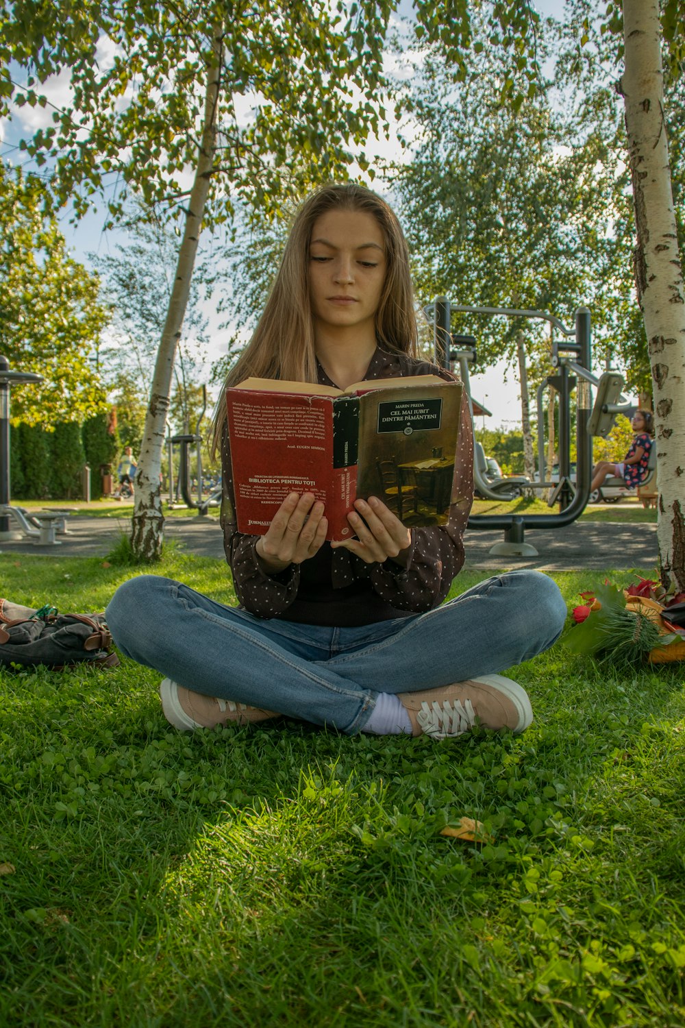 a woman sitting in the grass reading a book