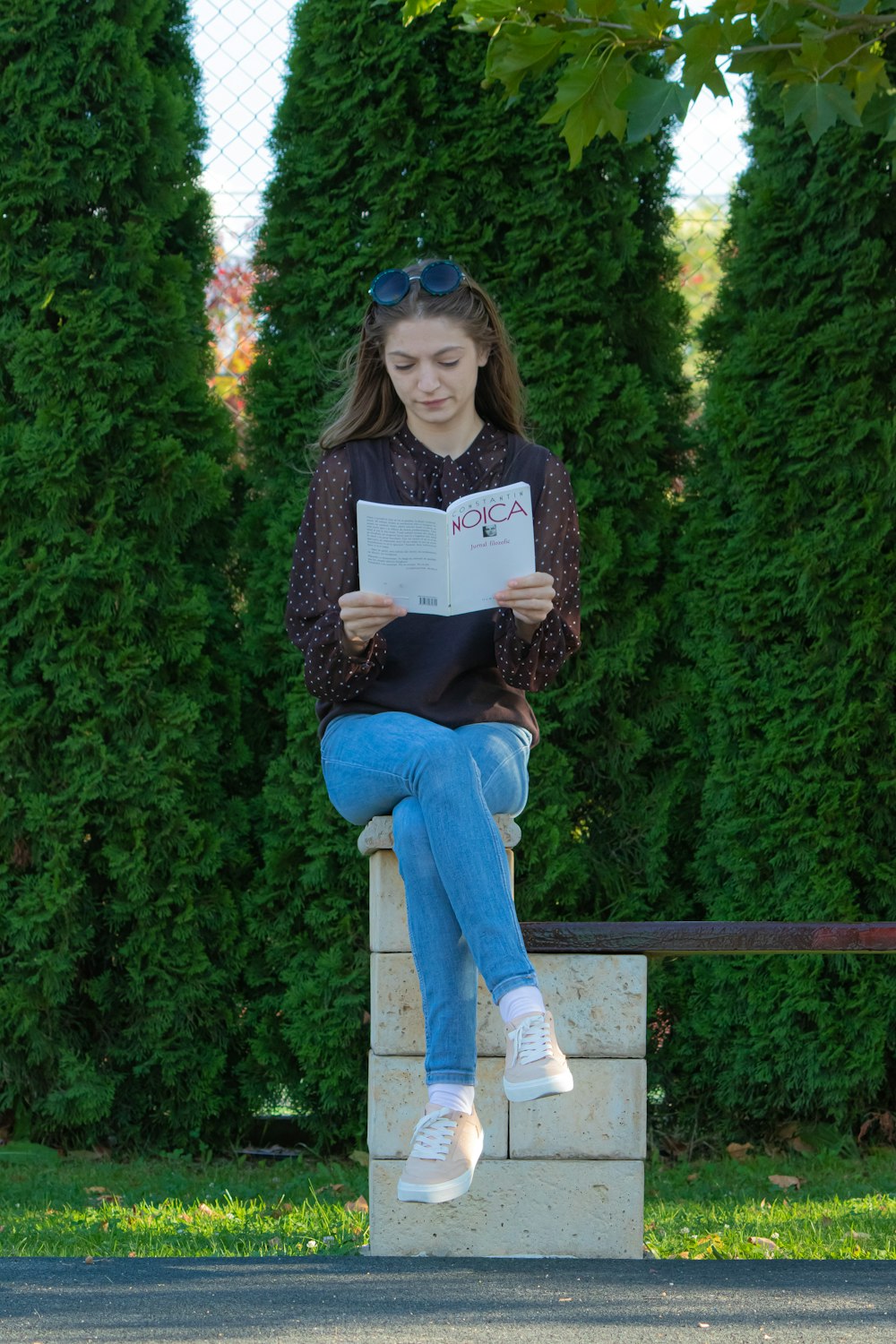 uma menina sentada em um banco lendo um livro