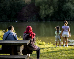 A serene family sitting together outdoors surrounded by lush greenery and soft sunlight.