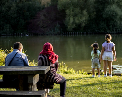 A family enjoying a picnic near a serene lake surrounded by rocky cliffs.