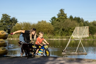 a woman and a child on a bike next to a lake