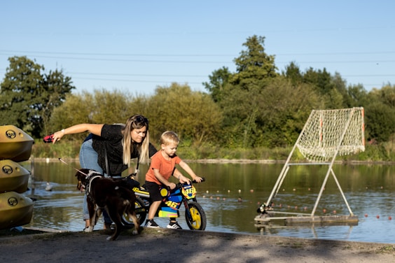 a woman and a child on a bike next to a lake