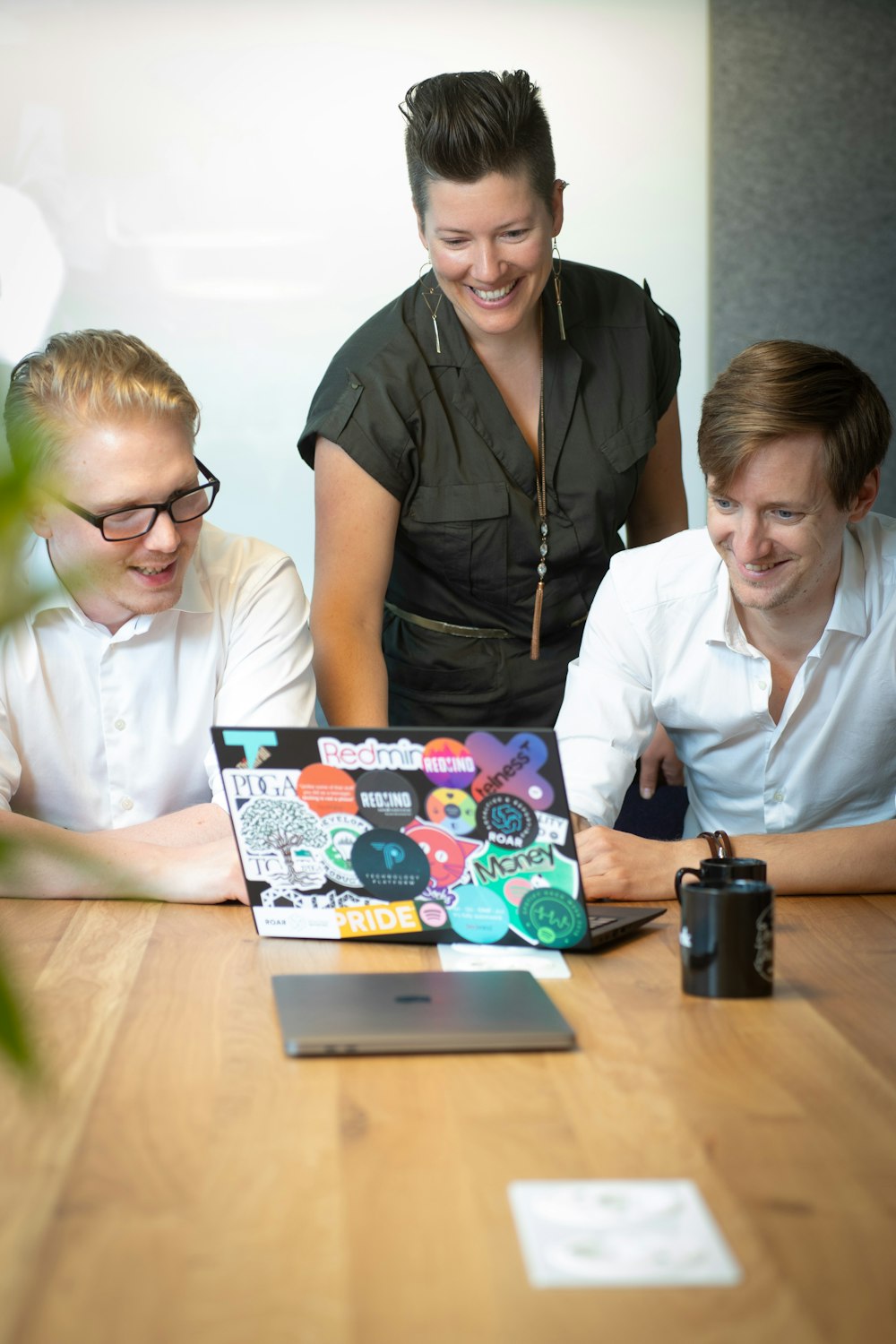 a group of people sitting around a table looking at a laptop