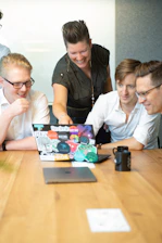 a group of people sitting around a table looking at a laptop