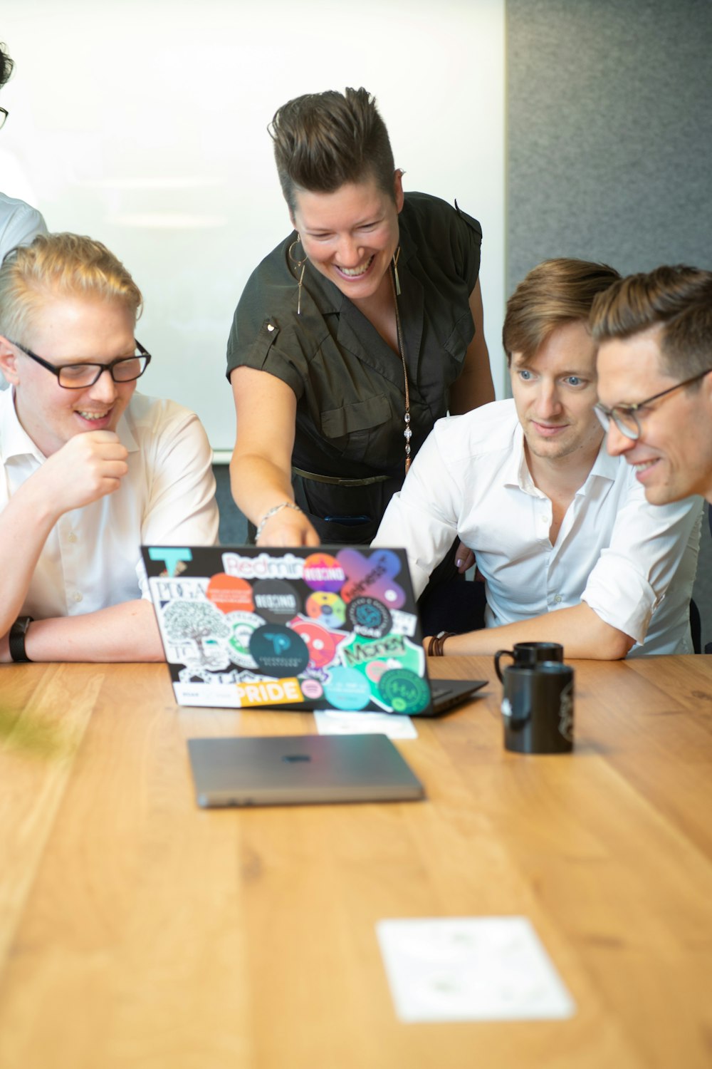 a group of people sitting around a table looking at a laptop