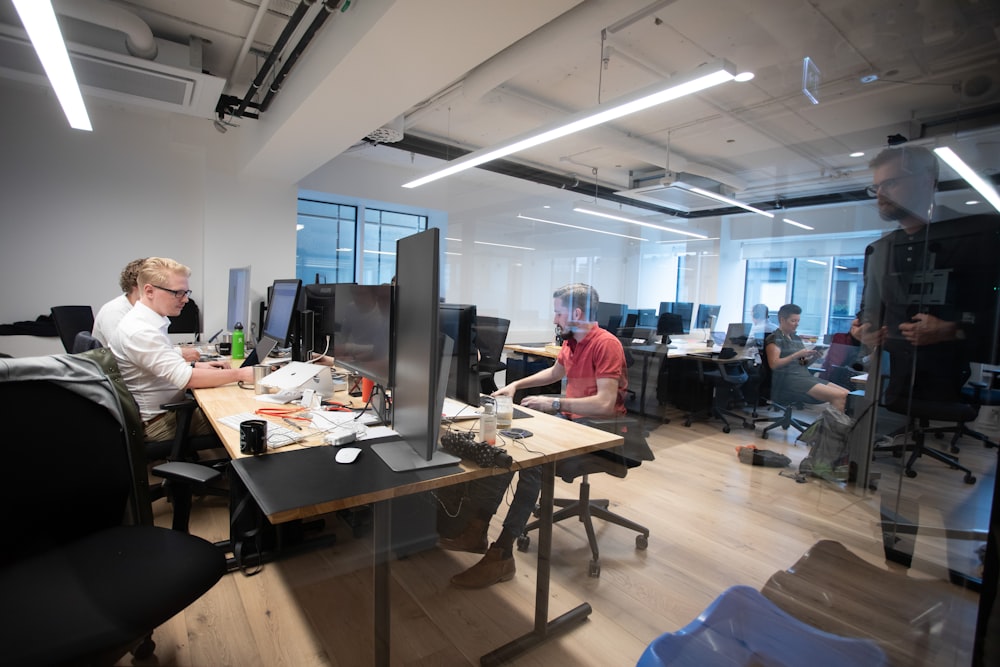 a group of people sitting at desks in an office