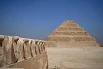 a stone wall with a pyramid in the background