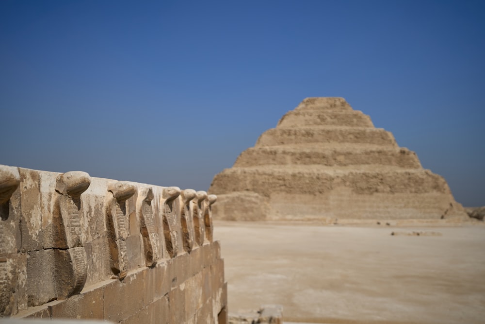 a stone wall with a pyramid in the background