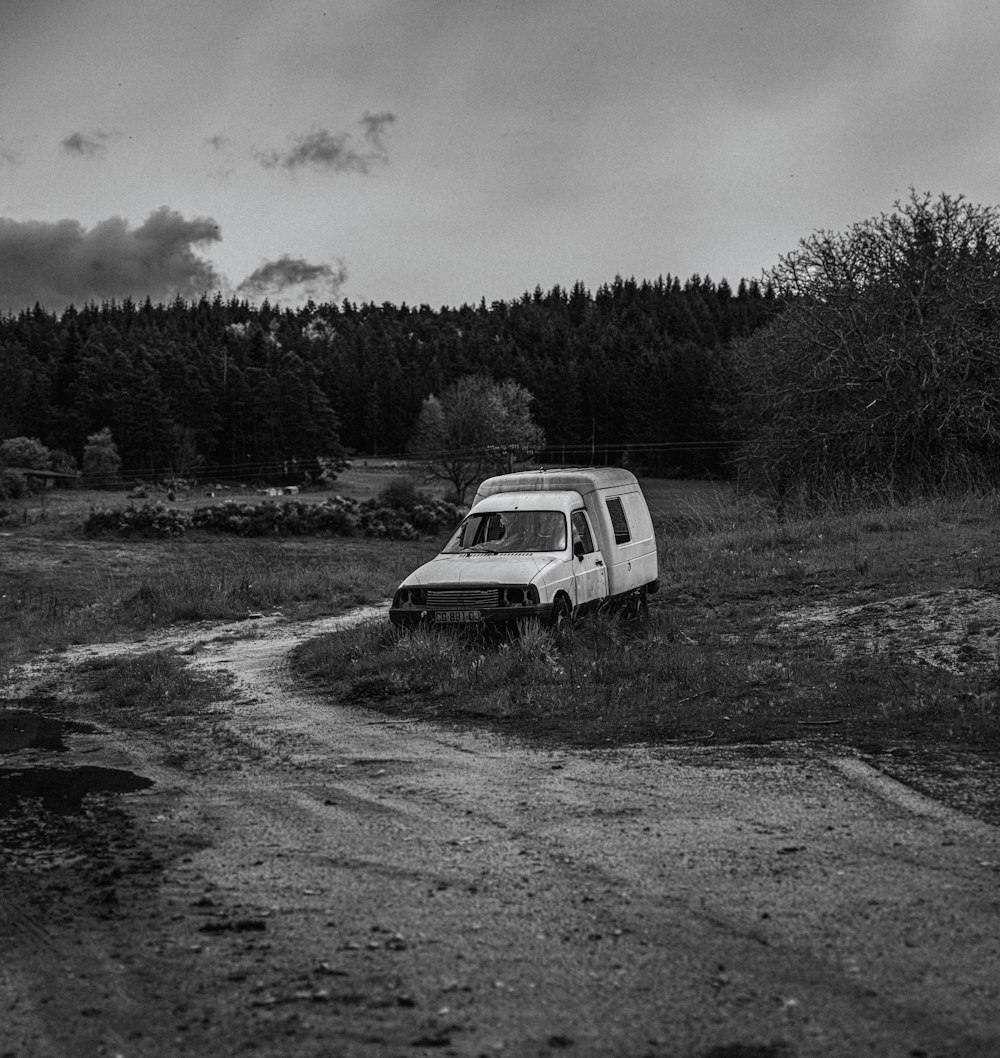 an old van is parked in the middle of a dirt road