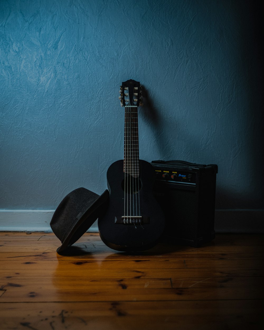 a guitar and a hat on a wooden floor
