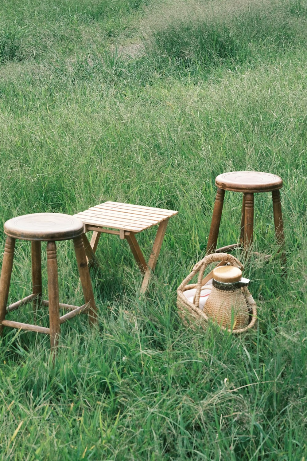 dos taburetes y una mesa en un campo cubierto de hierba