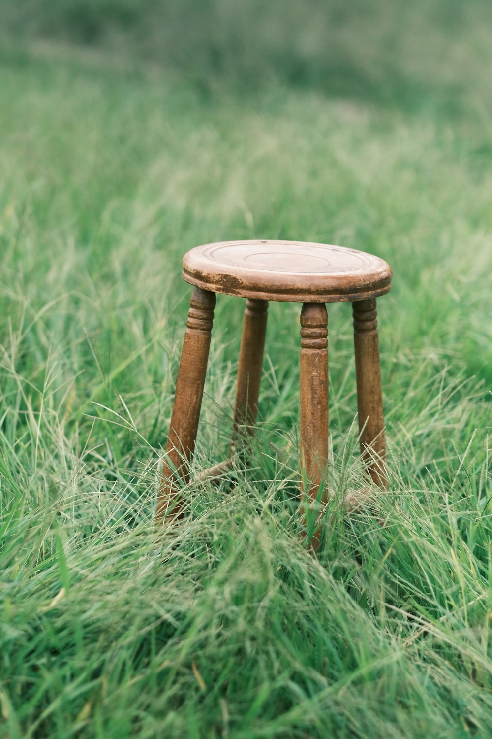 a small wooden stool in a grassy field