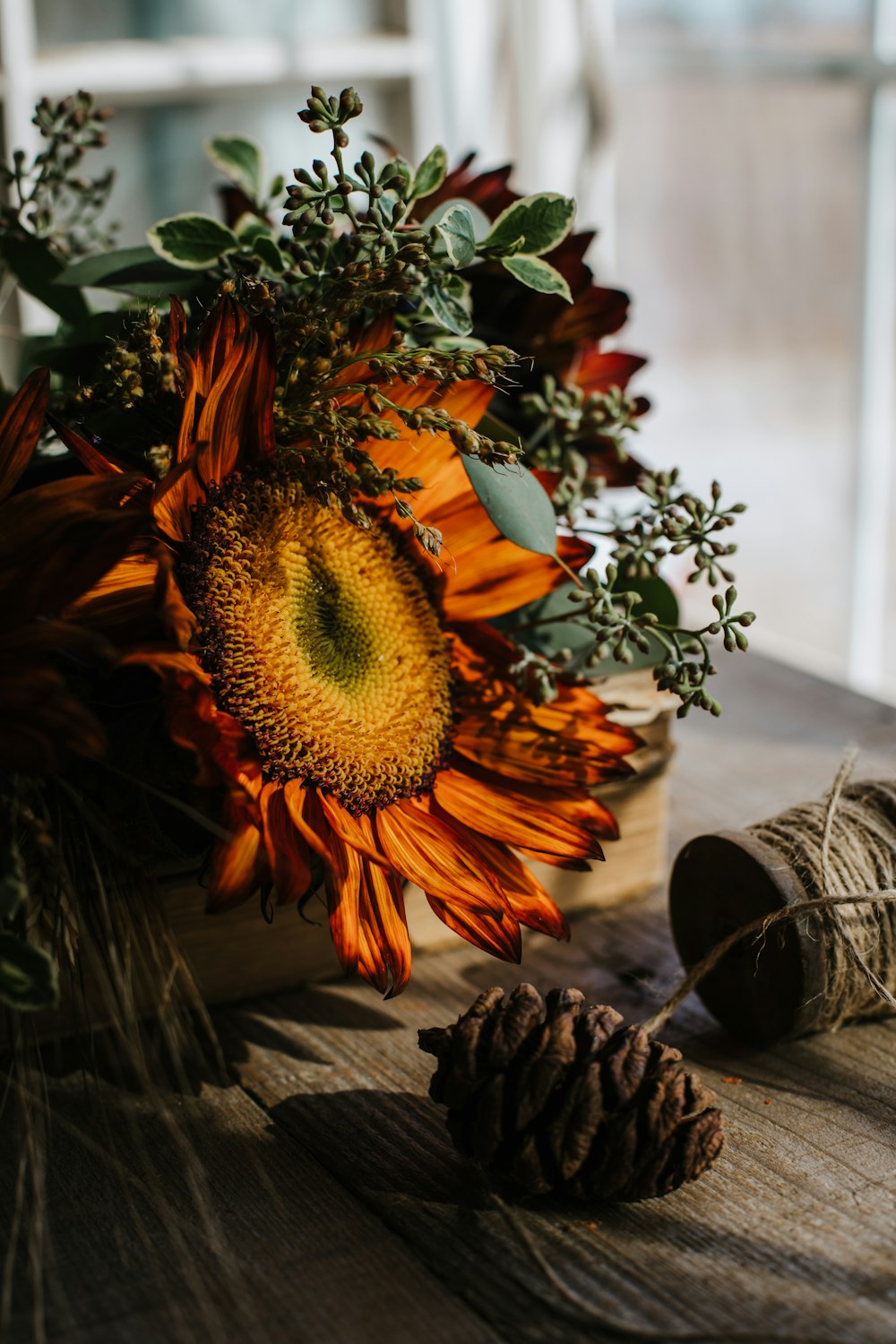 a bouquet of sunflowers and pine cones on a table