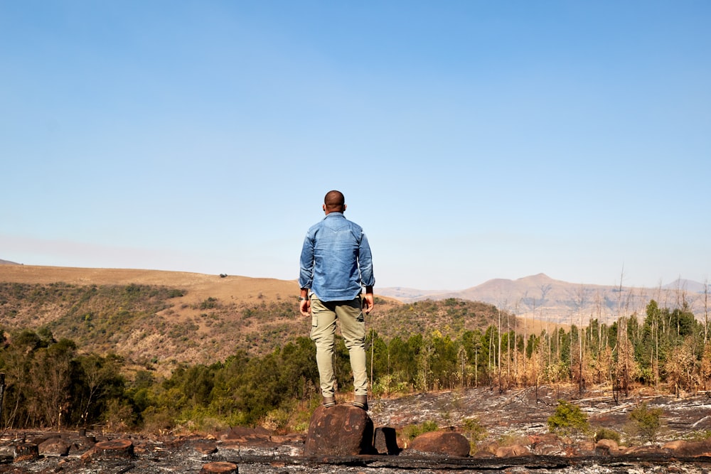 a man standing on top of a rock in the middle of a forest