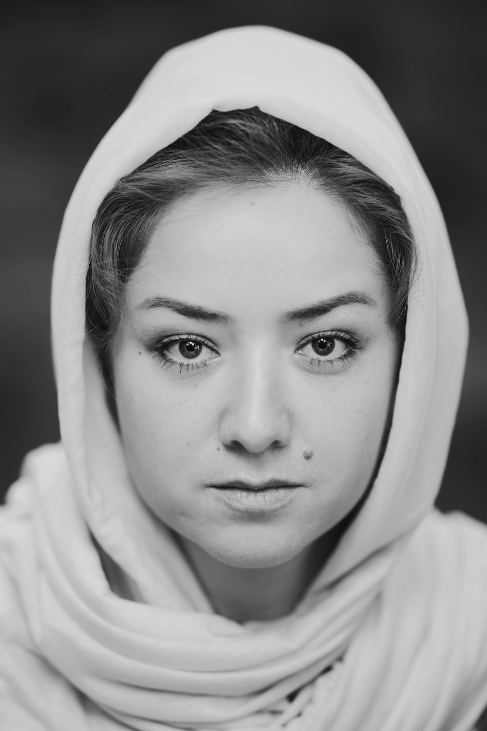 a black and white photo of a woman wearing a headscarf