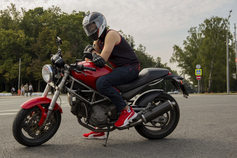 a woman is sitting on a red motorcycle
