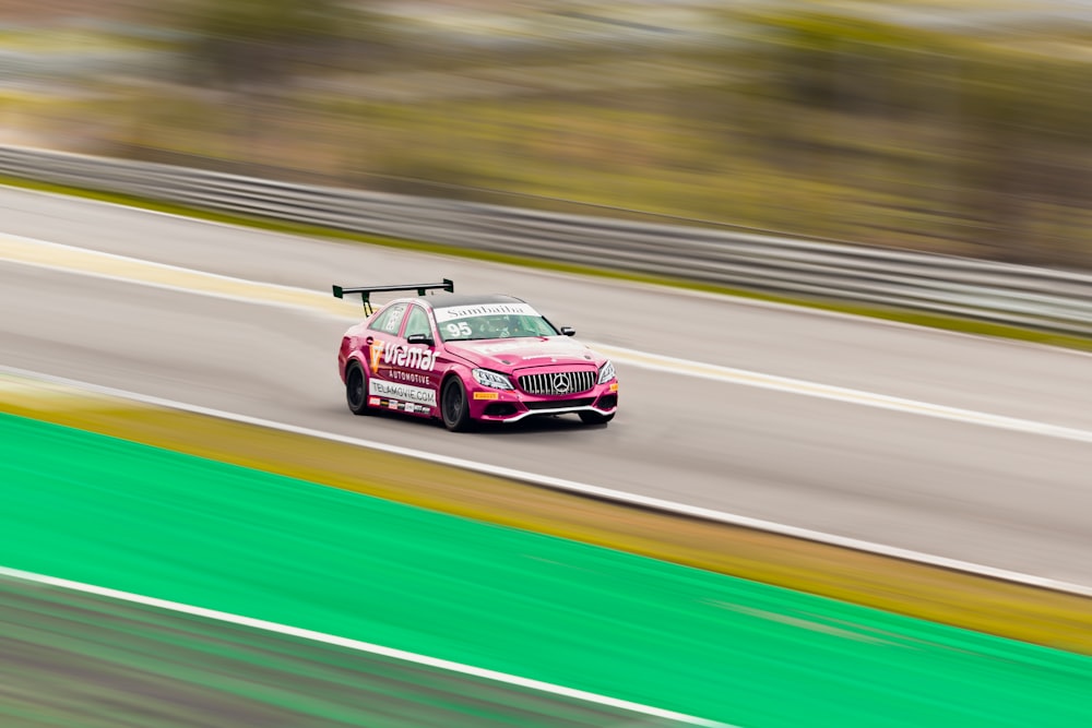 a pink car driving down a race track