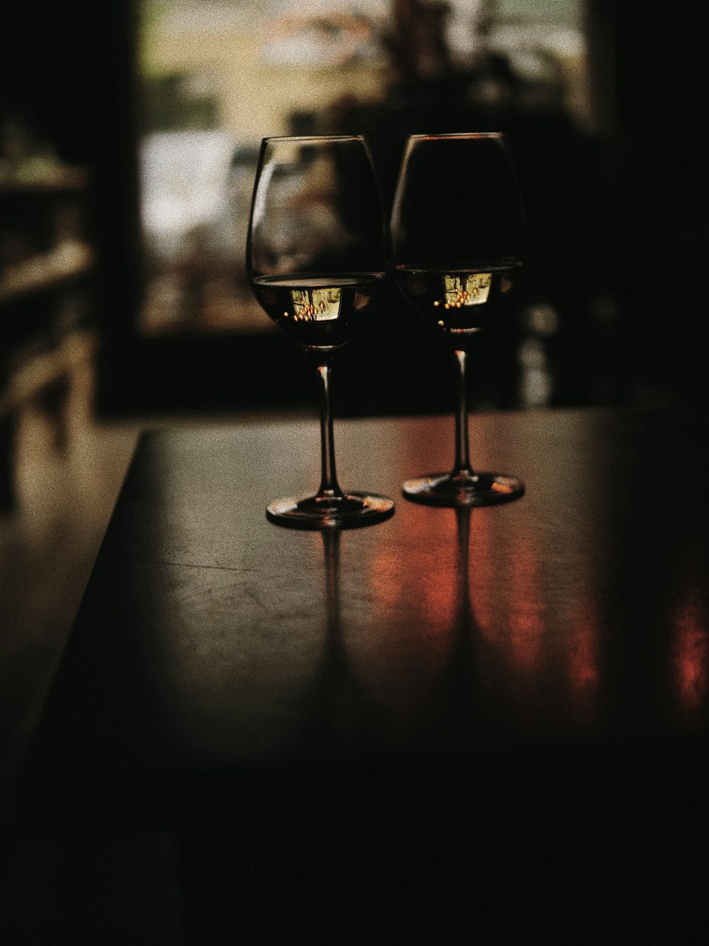 two wine glasses sitting on top of a wooden table
