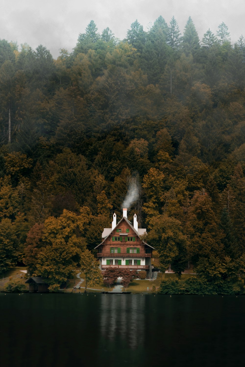 a house on the shore of a lake surrounded by trees