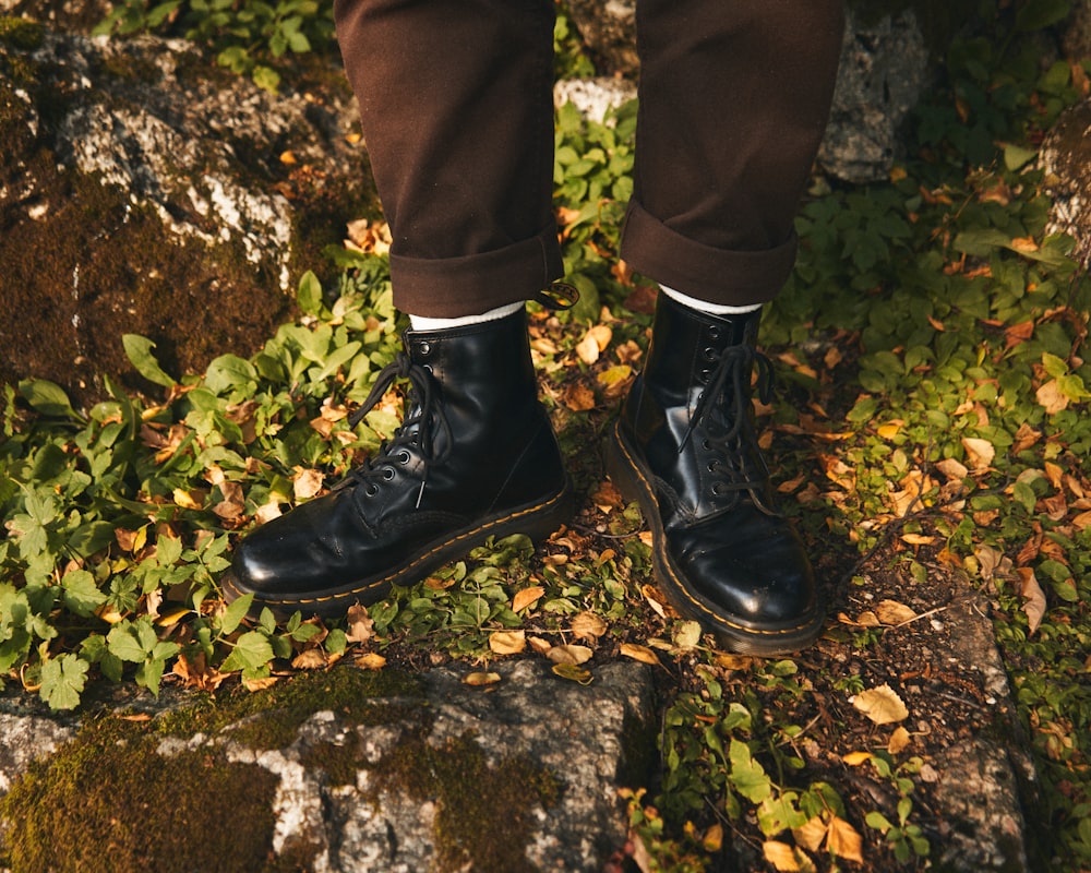 a person standing on a rock with a pair of black shoes