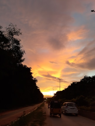 An Ertiga with company branding driving smoothly on a highway at sunset.