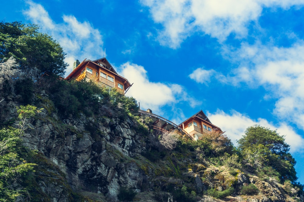 a house sitting on top of a mountain under a cloudy blue sky
