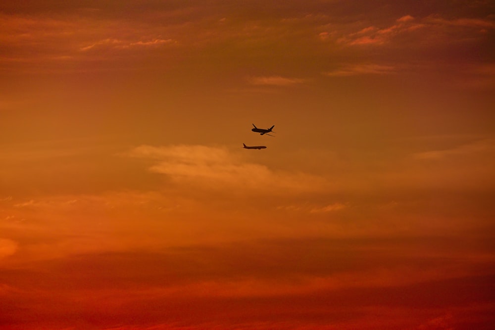 an airplane is flying in the sky at sunset