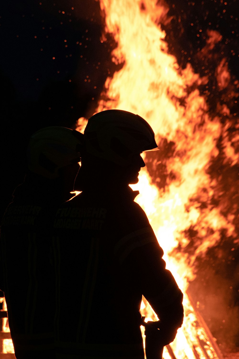 Un pompiere in piedi di fronte a un grande incendio