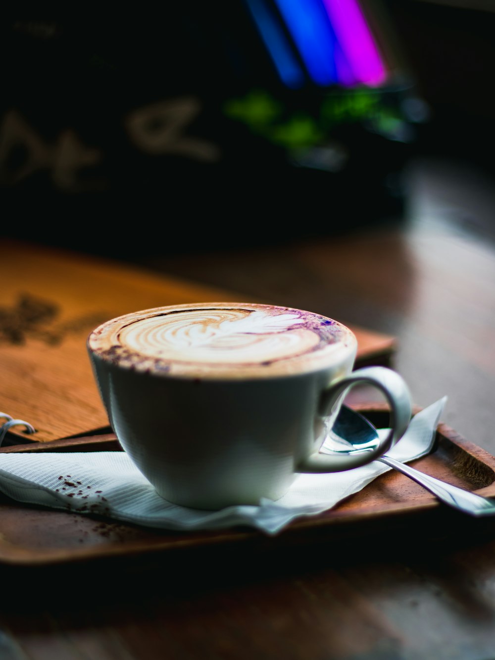 a cup of coffee sitting on top of a wooden tray