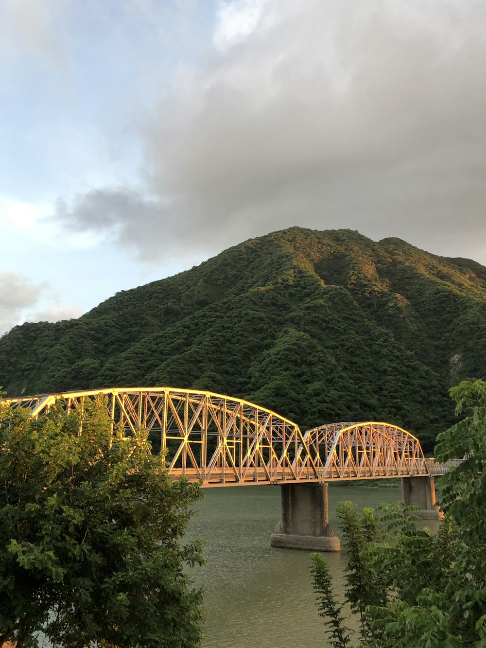 a bridge over a river with a mountain in the background