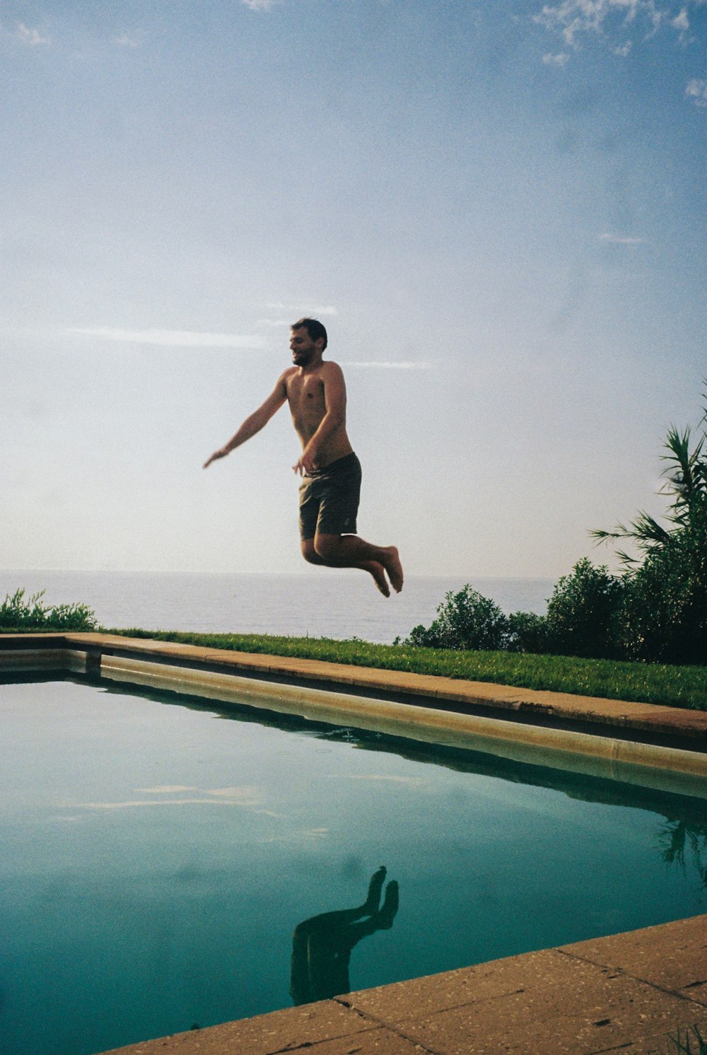 um homem pulando no ar perto de uma piscina