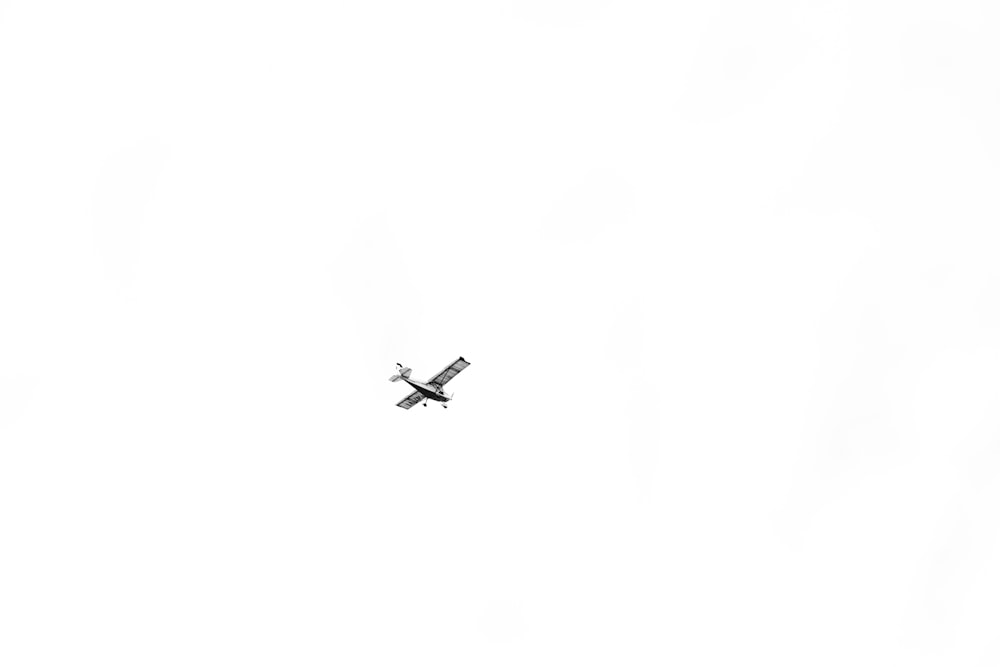 a small airplane flying through a white sky