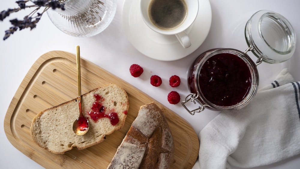 a loaf of bread with raspberry jam and a cup of coffee