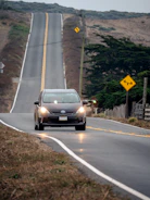a car driving down a road next to a hill
