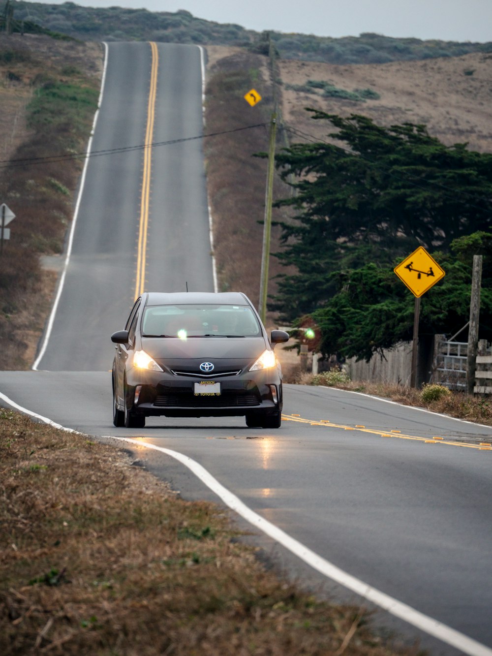 a car driving down a road next to a hill