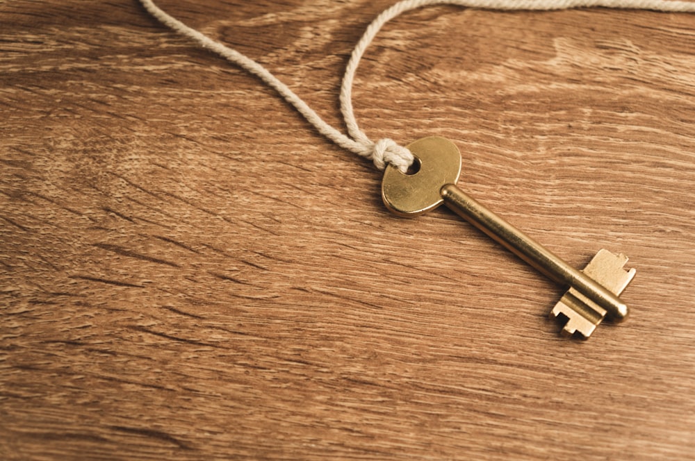 a golden key on a string on a wooden surface