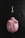 A pink piggy bank with white polka dots lying on a dark textured surface, accompanied by a golden key placed above it.