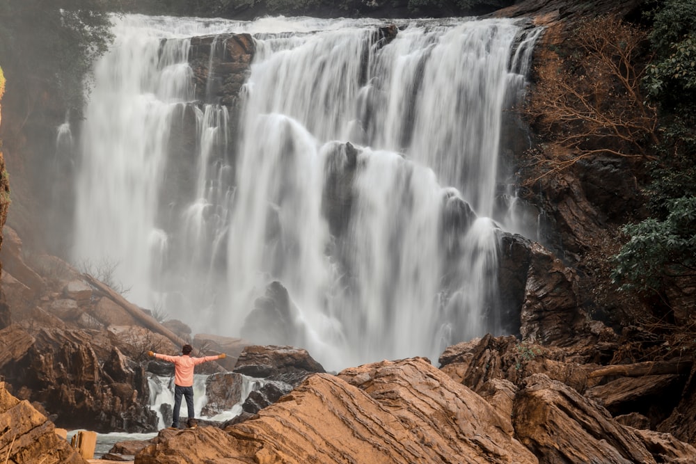 um homem em pé na frente de uma cachoeira