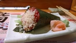 A vibrant roll of sushi topped with spicy mayo and crunchy tempura flakes.