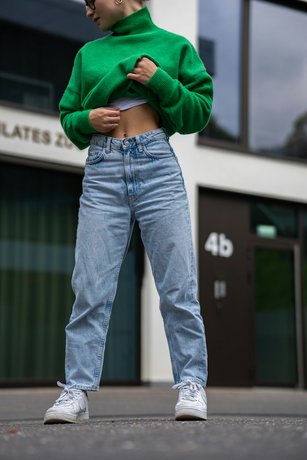 a woman wearing a green sweater and jeans