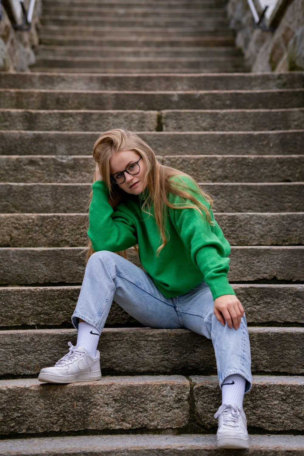 a woman in a green sweater sitting on some steps