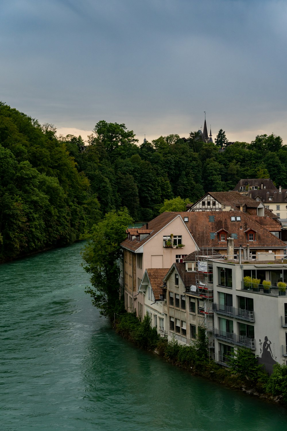 a river running through a city next to a lush green forest