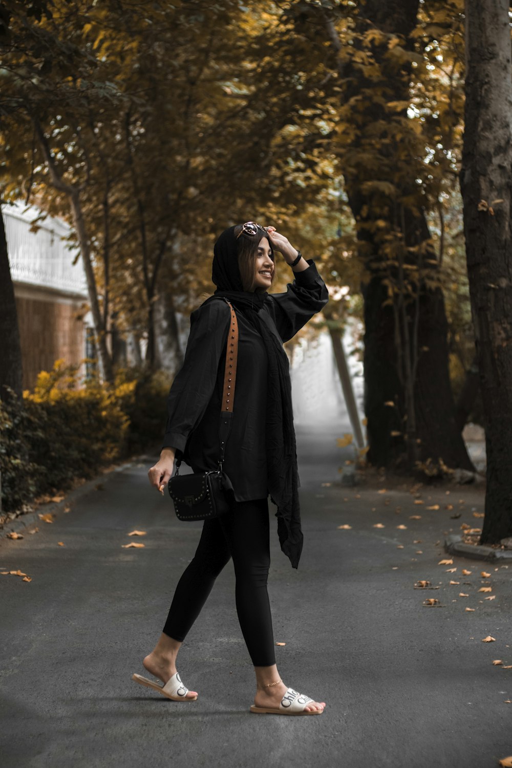 a woman walking down a road in a black jacket