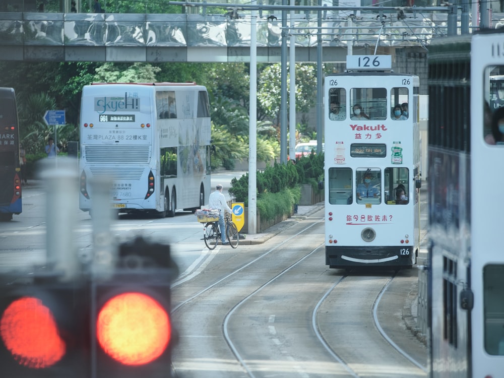 a couple of buses driving down a street next to a traffic light