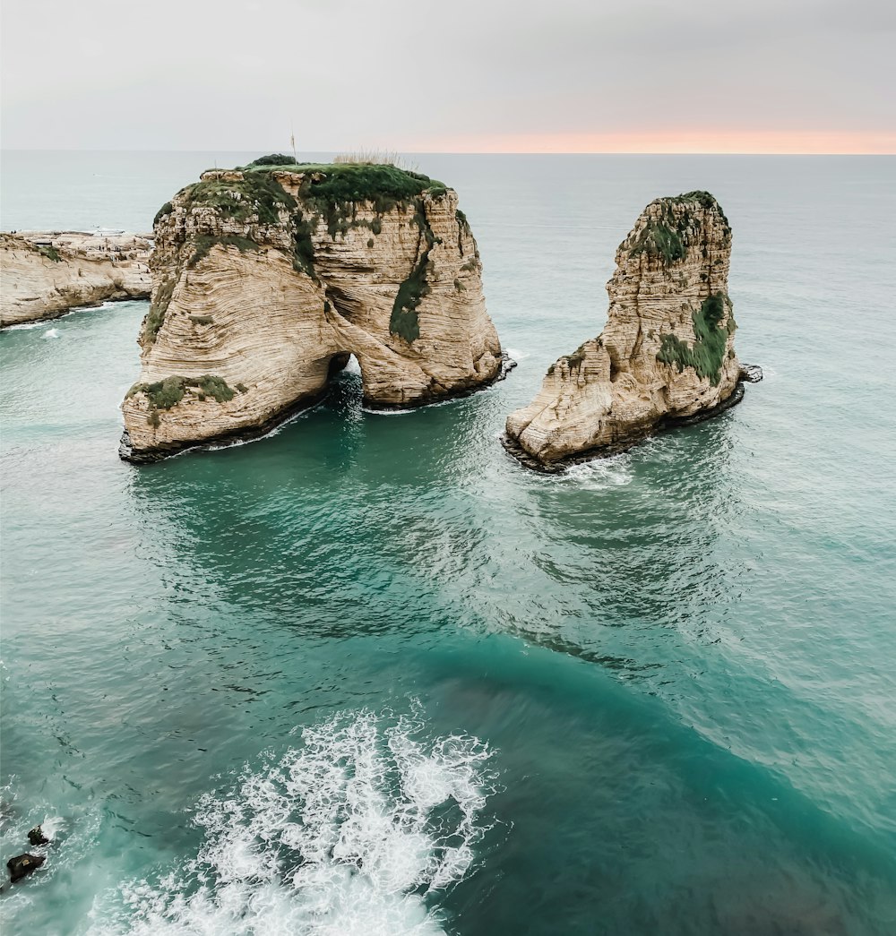 un paio di grandi rocce sedute nel mezzo di uno specchio d'acqua