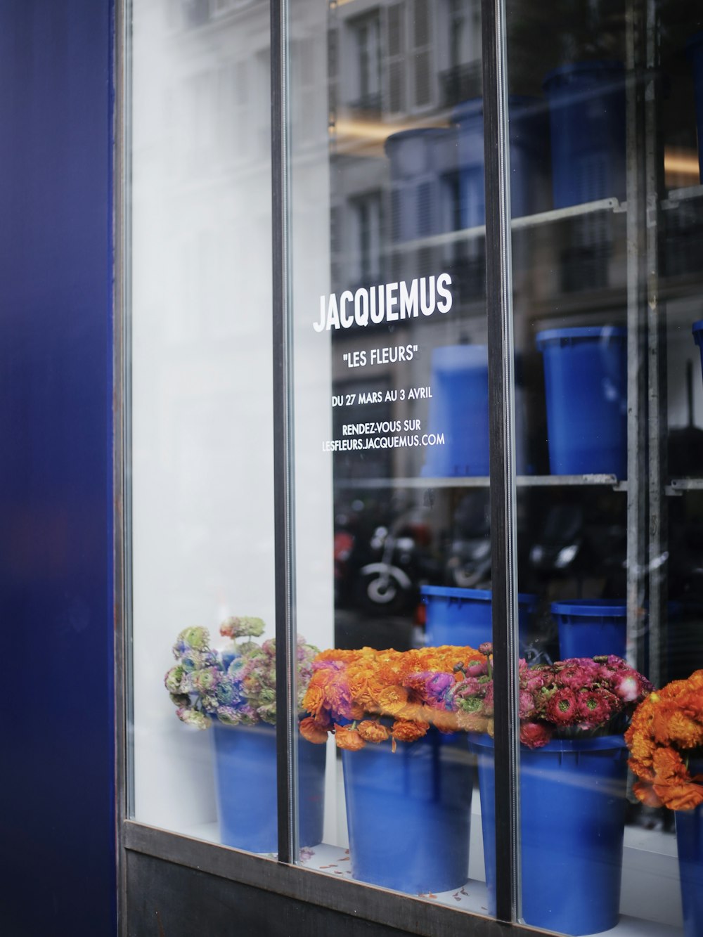 a store window with blue buckets of flowers in front of it
