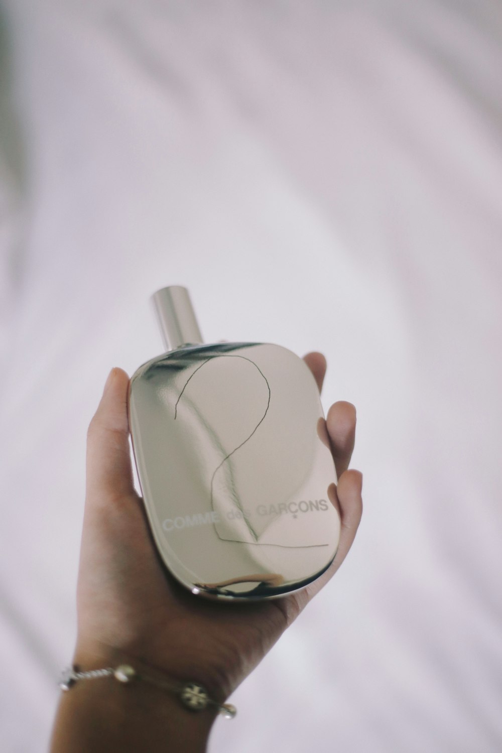 a person holding a white perfume bottle in their hand