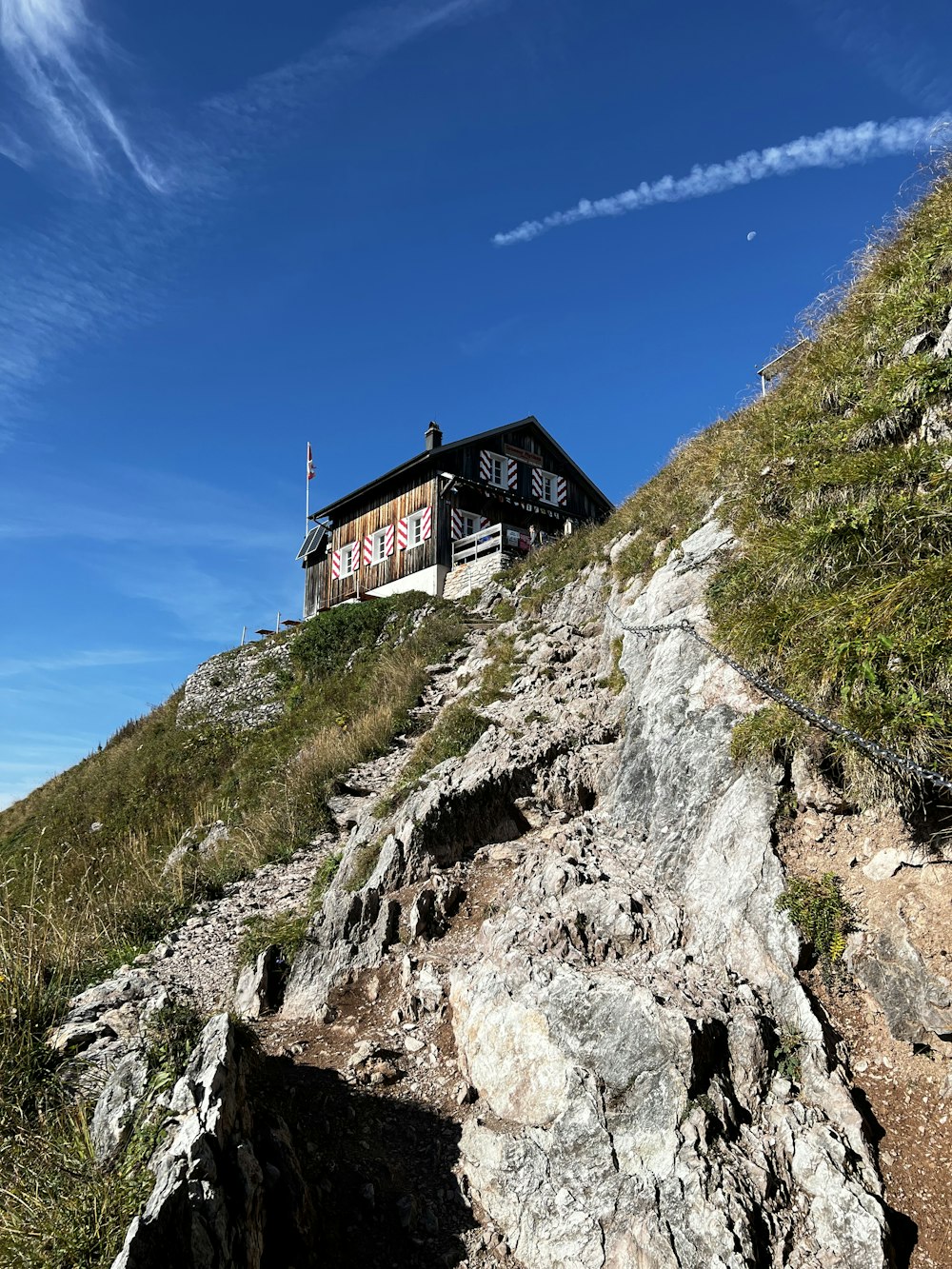 uma casa sentada no topo de uma colina rochosa