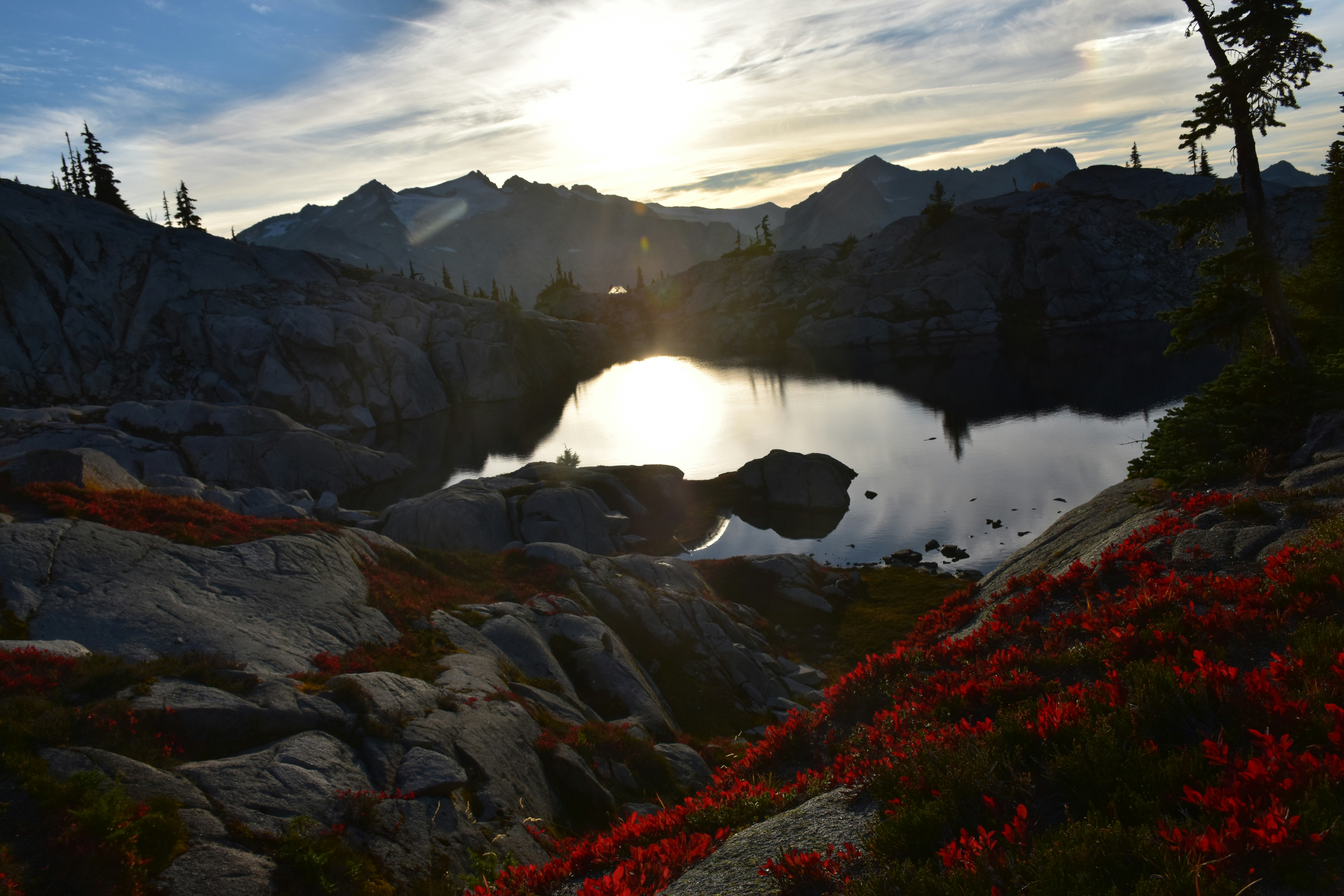 the sun is setting over a mountain lake, A cloudy sky before sunset reflecting off of Lower Robin Lake ablaze with fall colors, looking on towards Mount Daniel